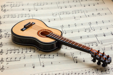 Little Acoustic guitar laying sheet music closeup