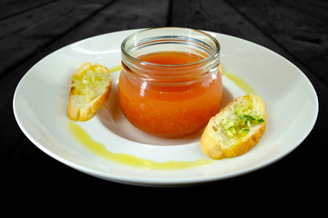 White plate with bowl of vegetarian soup decorated with slices of bread and olive oil.