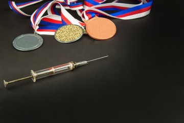 Syringe and medals. Doping in sport. Abuse of anabolic steroids for sports. Anabolic steroids spilled on a wooden table. Fraud in sports.
