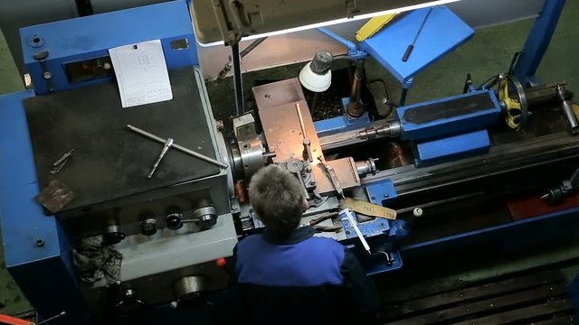 Worker operating in manual lathe