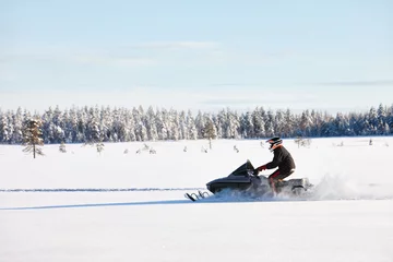 Fotobehang Man driving sports snowmobile in Finnish Lapland in a sunny day © kobeza