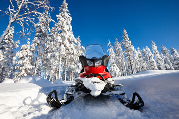 Red snowmobile in Finnish Lapland sunny landscape