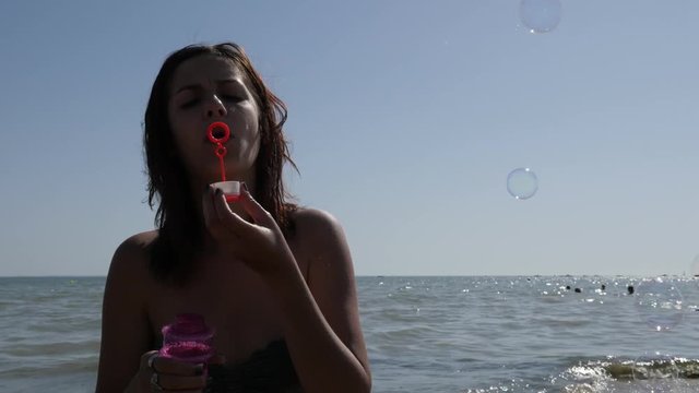 Enjoying summer with air balloons blowing near sea coast 4K 2160p 30fps UHD footage - Brunette playing with soap bubbles on the ocean beach 3840X2160 UltraHD video 