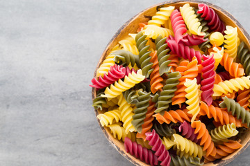 Macaroni pasta in a wooden bowl on a gray background.