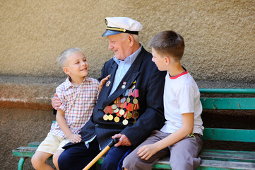 Obraz na płótnie Canvas WWII veteran with children. Grandchildren looking at grandfather