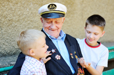 WWII veteran with children. Grandchildren looking at grandfather