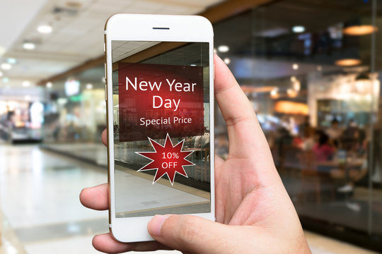 Augmented reality marketing concept. Hand holding smart phone use AR application for check promotion special price of restaurant in retail store in New year day