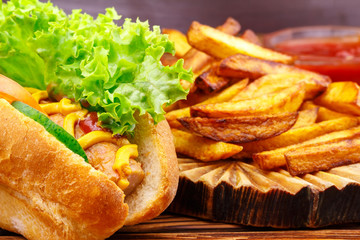 Fast food meal, hot dog, french fries and ketchup on wooden background.