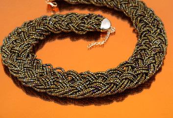 Dark glass bead collar on orange mirror background 