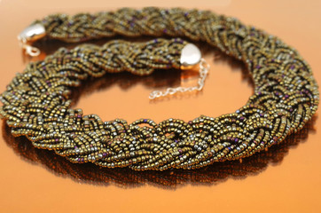 Dark glass bead collar on orange mirror background 
