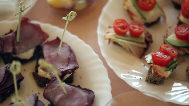 Dishes with beef canapes and vegetable sandwiches, the camera moves smoothly
