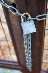 Rusty metal gate closed with padlock and chain