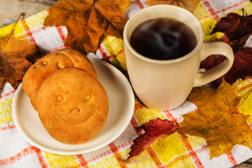 Hot drink, biscuits with a smile and autumn leaves