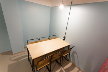 Prison style room with wooden table and chairs in a minimalistic design hostel
