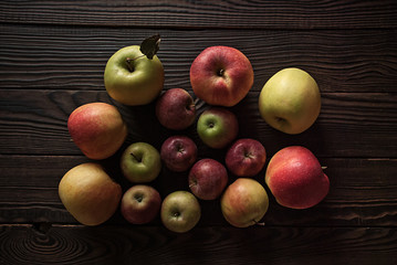Colored apples of different sizes on wooden surface
