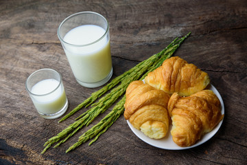 Croissant on dish with rice milk and ear of rice  on old wooden
