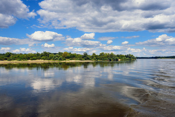 Vistula river in sunny summer day with reflections of clouds and blue sky. Poland, Europe.