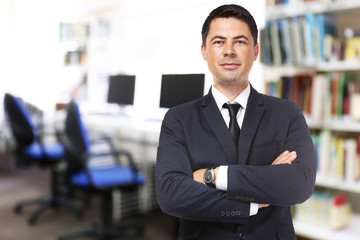 Male librarian on blurred reading room background