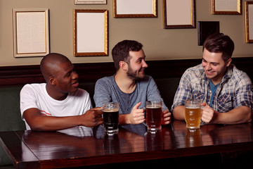 Happy friends drinking beer in pub