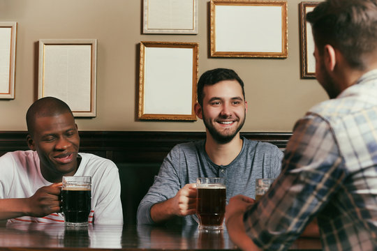Happy friends drinking beer in pub