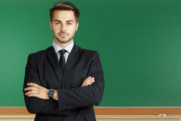Young teacher on chalkboard background. School and education concept.