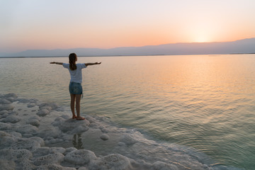 The girl on the shore of the Dead Sea in Israel at sunrise