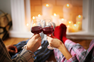 Couple drinking wine in front of fireplace at home