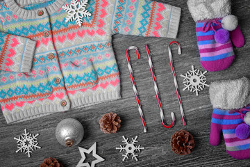 Set of winter clothes with Christmas decor on wooden background