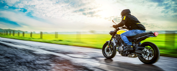 Motorrad fährt auf freier Landstrasse in den Sonnenuntergang