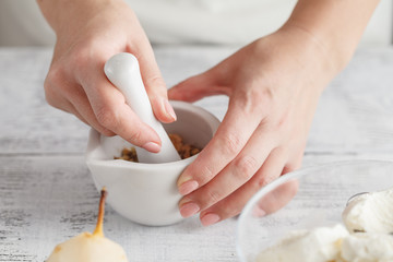 Woman hands with mortar with herbs on bright background
