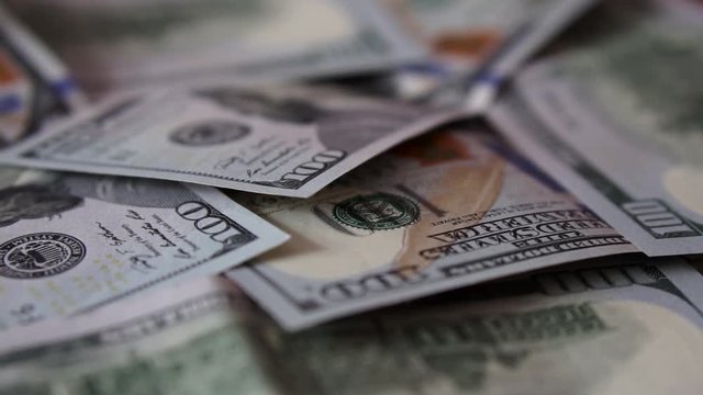 Backward direction close up dolly shot of scattered American paper money bills