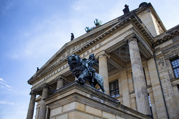 Fototapeta na wymiar Angel plays instrument while riding lion statue in front of Konzerthaus Berlin. Made by Ankeeta Bansal in 1821. Classical building with ornate halls for orchestral concerts & chamber music.