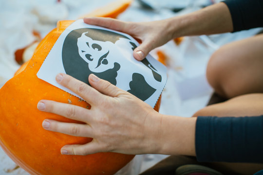 Boy making Halloween pumpkin outdoors.