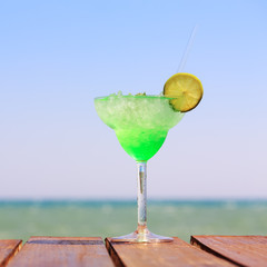 Green fairy cocktail on the wooden pier. Concept of exotic cockt