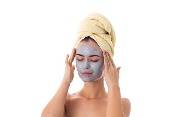 Woman with towel on her head and cosmetic mask on her face 