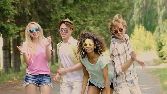 Four multiracial friends enjoying open-air music festival, dancing and jumping