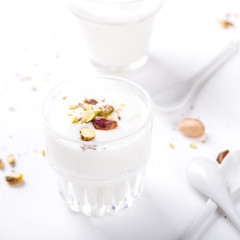 Yogurt in glass cups with nuts,pistachios.Breakfast,Dessert, Pudding on a white background.Food or Healthy diet concept.selective focus.Top view.