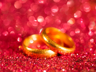 Old golden wedding rings on blurred red sparkle background