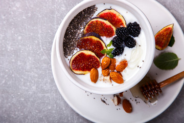 Homemade yoghurt, sour cream with fresh figs,fresh blackberries,Chia seeds and nuts almonds and mint.Healthy Breakfast.Food or Healthy diet concept. selective focus.