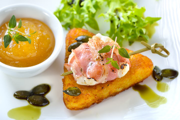 Ziegenkäse im Speckmantel auf Rösti mit Kürbiskernen, Feigensenf und Salat mit Kürbiskernöl - Roasted goat cheese wrapped in bacon served on crispy hash browns, pumpkin seeds, salad and fig mustard