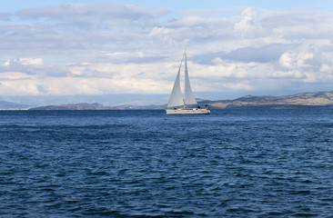 Obraz premium White yacht gliding through a blue bay