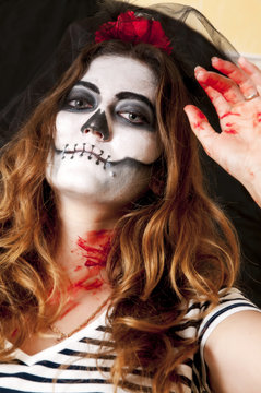 Portrait of young woman with terrifying makeup. Halloween holidays masquerade concept. Mexican celebration of the Day of the Dead Dia de los Muertos and the Roman Catholic holiday All Souls Day