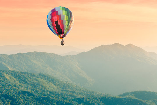 Hot air balloon above high mountain landscape at sunset