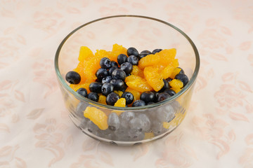 Fresh blueberries and canned mandarin oranges in glass bowl