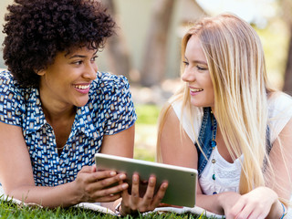Two young women with tablet in park