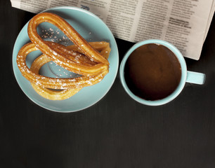 Traditional Spanish churros, chocolate, blurred newspaper, copys