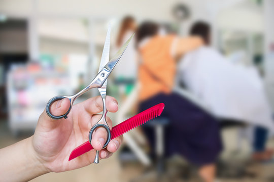 Hairdresser hold scissors with salon beauty background