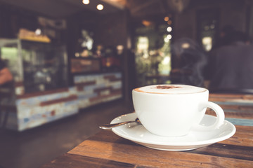 Cup of hot coffee on table in cafe with people. vintage and retro color effect - shallow depth of...