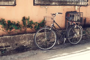 Schilderijen op glas vintage bicycle parked at old wall in the urban narrow street (vintage color tone styles) © jakkapan