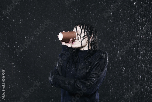 “Woman standing in rain, drinking coffee.” Stock photo and royalty-free